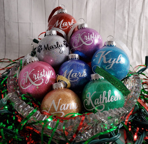 Personalized tree ornaments (plastic). Your choice of glitter color and ribbon color.  Has appropriate year on back.
Ornament glitter choices: Gold, Multi-colored glitter, Purple, Turquoise, Green, Pink, Blue, Red.
Ribbon Choices: Red, Green, Blue, Silver, Gold
