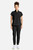 The HH752 Quest Bella Women’s Partial Zip Stand Collar Top appears in a sleek black uniform set paired with black pants and white sneakers. The minimalist partial‑zip collar and short‑sleeve silhouette highlight a contemporary, functional style suited for medical, service, and fast‑paced workplace settings.