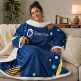 A cozy navy blanket with polka dots and stripes, featuring a soft white collar, draped over a person sitting on a sofa.