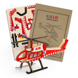 A wooden model helicopter in red and white, accompanied by assembly pieces and instructions. Features a logo.
