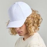 A white cap with a curved brim, positioned on a person with curly blonde hair, facing slightly sideways.