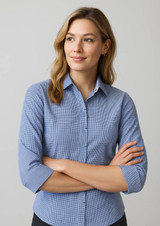 A women's button-up shirt in blue with a subtle checked pattern and 3/4 sleeves, featuring a logo.
