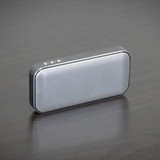 A grey Bluetooth speaker power bank with a sleek design and a textured surface, featuring a logo on the side.