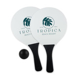 A paddle bat and ball set featuring two white paddles with black handles and a black ball, branded with a logo.