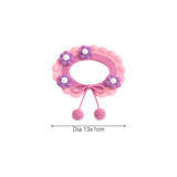 A pink and purple crochet pet bib with floral embellishments and decorative pom poms. Features a circular design measuring 13cm diameter.