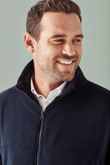A navy men's plain micro fleece jacket with a zip collar, featuring a branding logo.