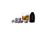 A drink glass filled with whisky and ice cubes, alongside a bag containing whisky rocks. The rocks are grey in colour.