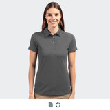A women's polo shirt in dark grey, featuring a collar and logo. The model is smiling and facing forward.