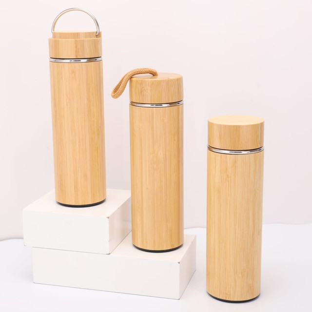 A drink bottle trio in natural bamboo finish, featuring metal accents and various styles, displayed on a white platform.