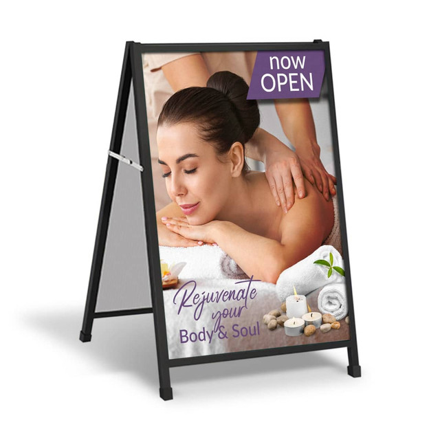 A-frame sign featuring a spa image with a relaxing massage scene, surrounded by candles and stones. Black frame.