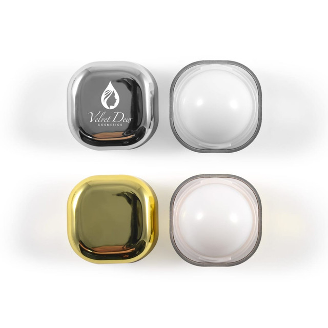 Two sets of square lip balm containers, one silver and black, one gold and white, with a logo on the silver container.