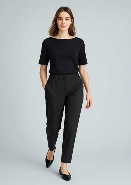 A woman wearing black slacks and a black top, walking confidently with her hands in the pockets of the pants.