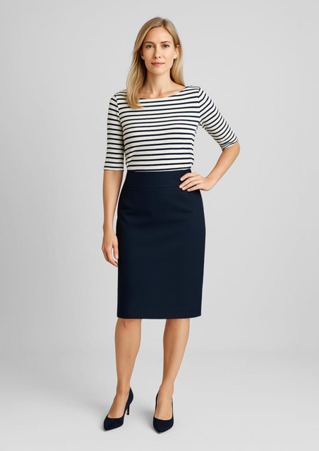 A woman stands in a relaxed fit, lined skirt in navy, paired with a striped top and heels. The image features branding.