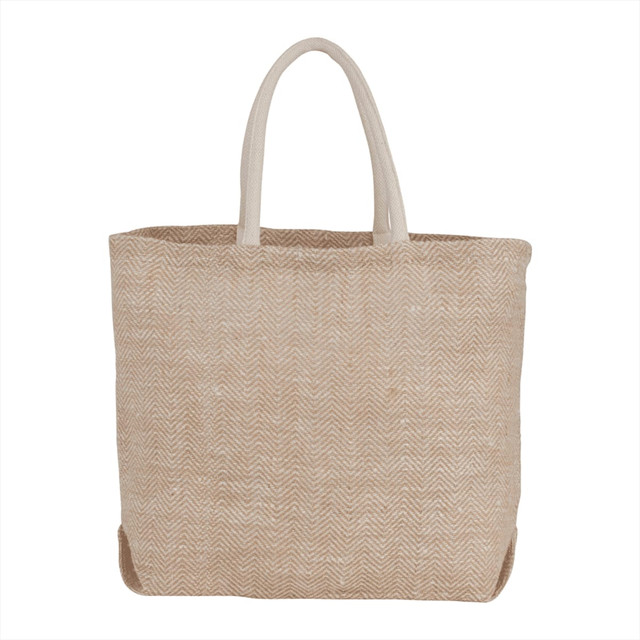 A herringbone patterned jute tote bag in beige with light cream handles. It features a logo on the front.