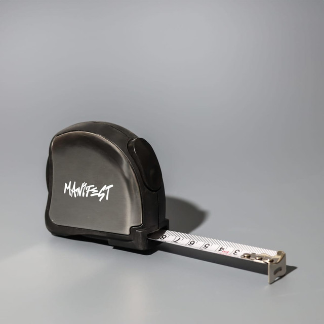 A black tape measure with a retractable white measuring tape and a logo on the side.