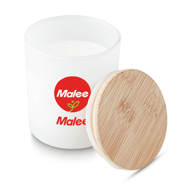 A small white candle in a glass container with a wooden lid, featuring a logo on the side.