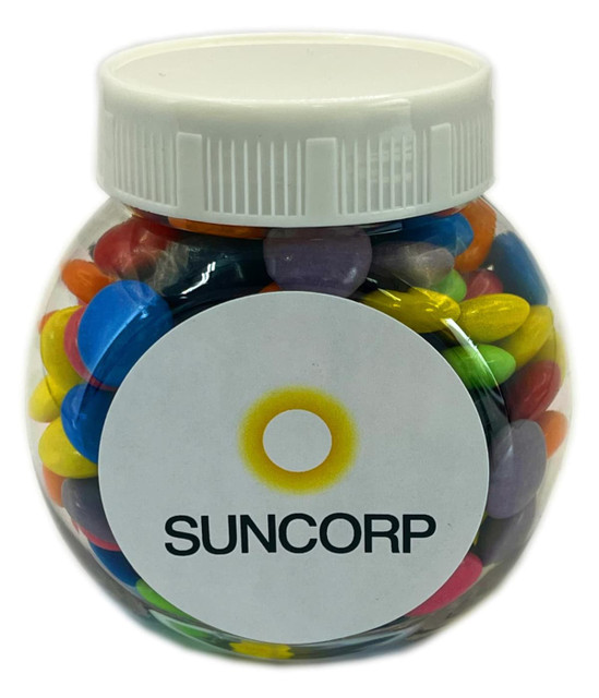 A plastic jar filled with colourful choc beans, featuring a white lid and a logo on the front.
