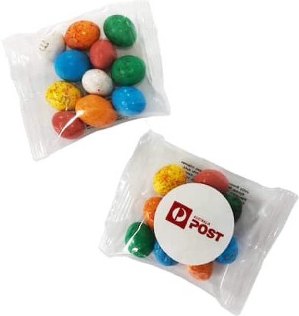 A transparent bag containing colourful chocolate-coated eggs in various shades, featuring a logo on the packaging.