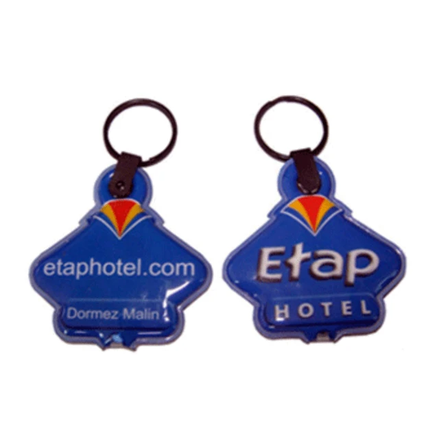 A blue PVC keyring featuring an LED light and a logo, attached to a metal keychain.