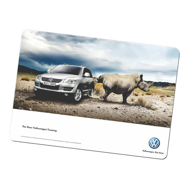 A counter mat featuring a grey SUV beside a rhinoceros in a desert landscape, with a logo at the bottom.
