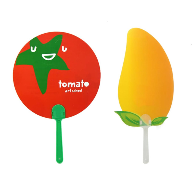 A red round hand fan with a green star design and a yellow fan shaped like a mango with green leaves.