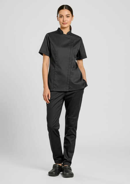 A woman wearing a black chef uniform consisting of a short-sleeve shirt and jogger pants, with a logo on the shirt.