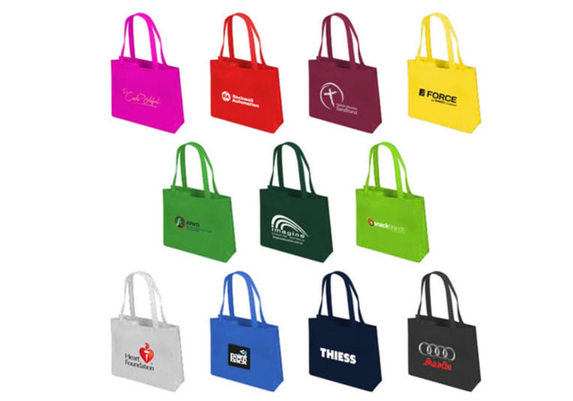 A variety of tote bags in different colours including pink, yellow, green, blue, and black, featuring various logos.