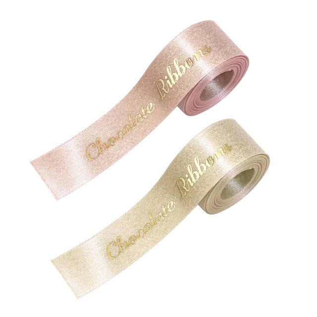 Two rolls of satin ribbon in pale pink and light gold, both with the text "Chocolate Ribbon" in gold lettering.