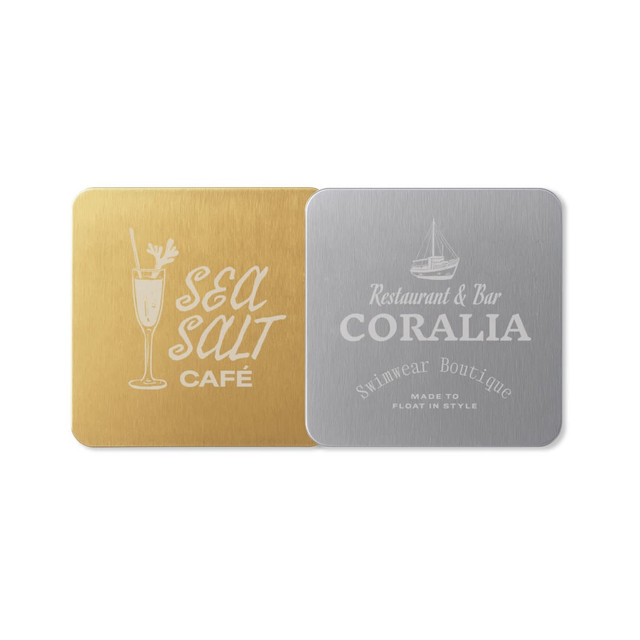 A square metal coaster featuring a gold finish on one side and a silver finish on the other, both with logos.