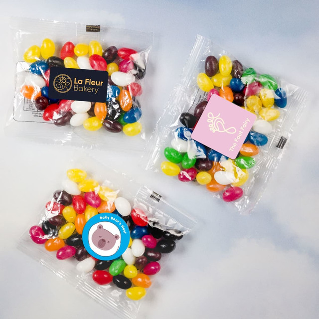 Assorted mini jelly beans in various colours, packed in clear cello bags with branding present.