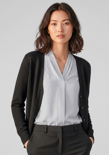 A black knit cardigan worn over a light blue blouse, styled with tailored black trousers. The model has shoulder-length hair.