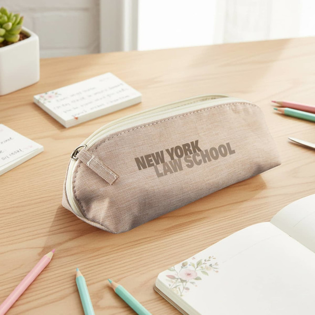 A beige pencil case with a zip closure sits on a wooden desk among stationery and notepads. It features a logo.
