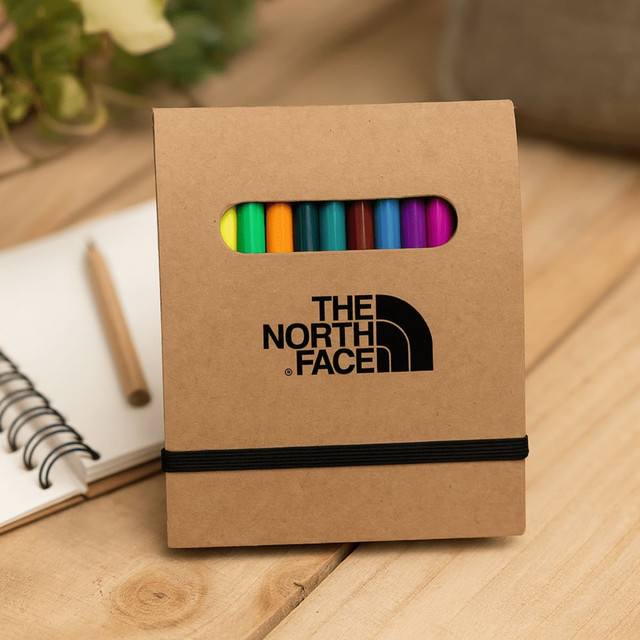 A notepad set in a brown cardboard cover with an elastic band, featuring colourful markers inside. It has a logo on the front.