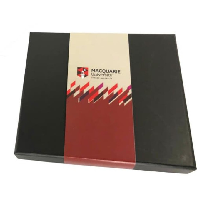 A black gift box featuring a red and white label with a logo, containing assorted chocolates or truffles.