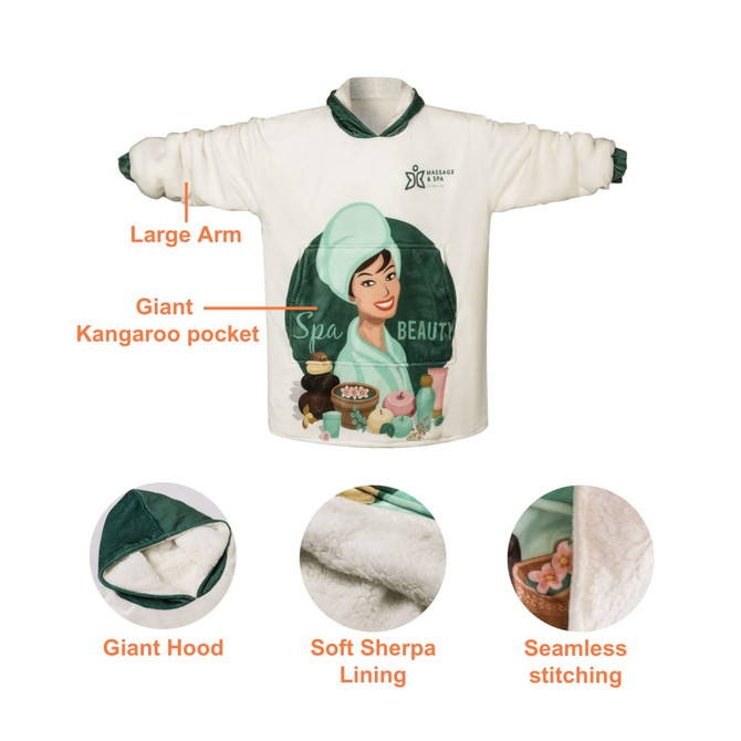 A wearable blanket in cream with a green hood and accents, featuring a large kangaroo pocket and soft sherpa lining.