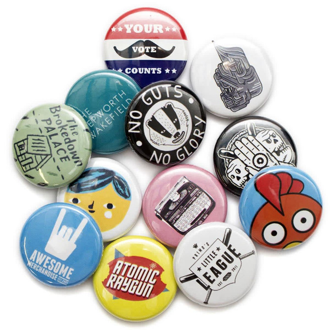 A collection of button badges in various colours, featuring diverse designs and logos.