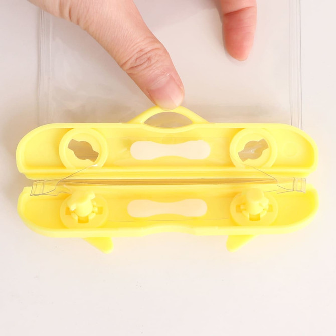 A yellow waterproof mobile pouch with a sealing mechanism, held by a hand. Features clear sides for visibility.