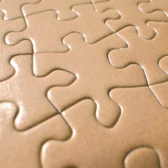 A close-up of beige jigsaw puzzle pieces with interlocking designs, featuring a smooth surface and subtle texture.
