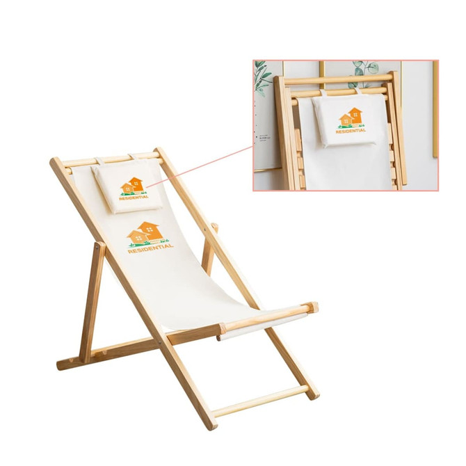 A wooden beach chair in natural tones, featuring a light canvas seat and a small headrest pillow. It has a logo.