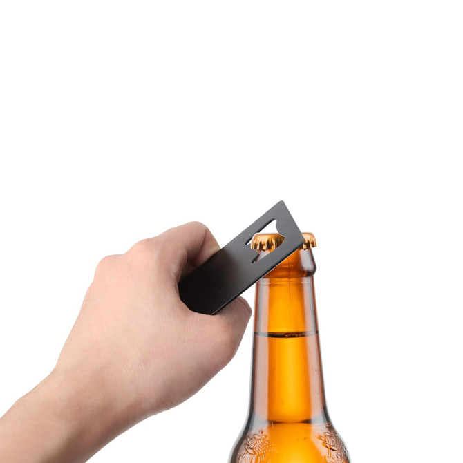 A drink bottle opener shaped like a card, in a sleek black finish, being used to open a beer bottle.