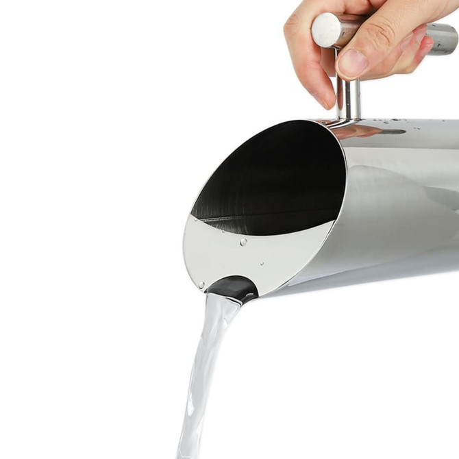 A stainless steel pitcher pouring water, featuring a sleek design and shiny finish, with a handle for easy gripping.