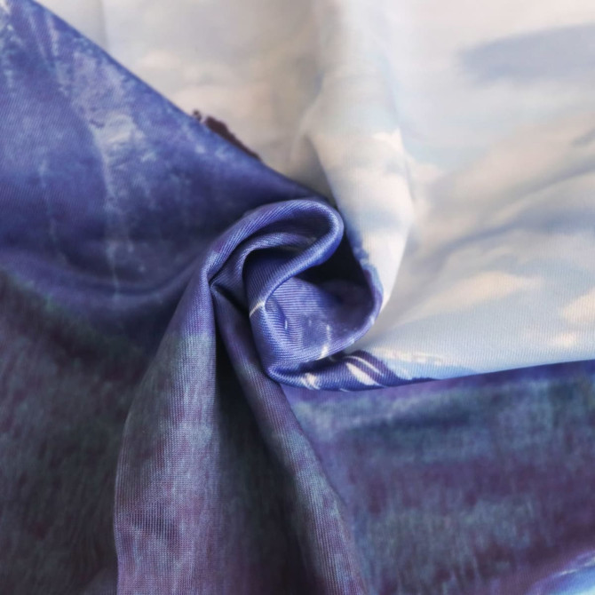 A close-up of a fabric featuring a blend of blue and purple tones, showcasing a silky texture and abstract design.
