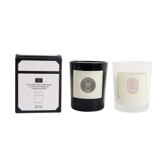 A black and white glass candle set displayed with a box, featuring a logo on each candle and a label with design information.
