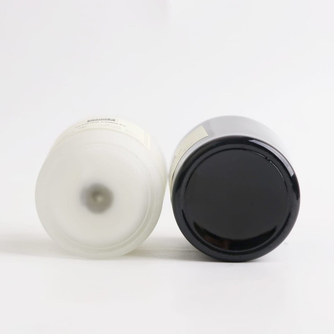 A 2.2oz glass candle in black and white, featuring a simple design and a logo on the bottom.