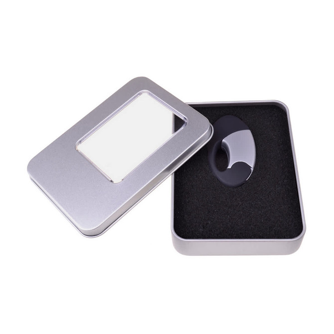A large silver tin case with a transparent window, containing a black item on cushioned black foam.