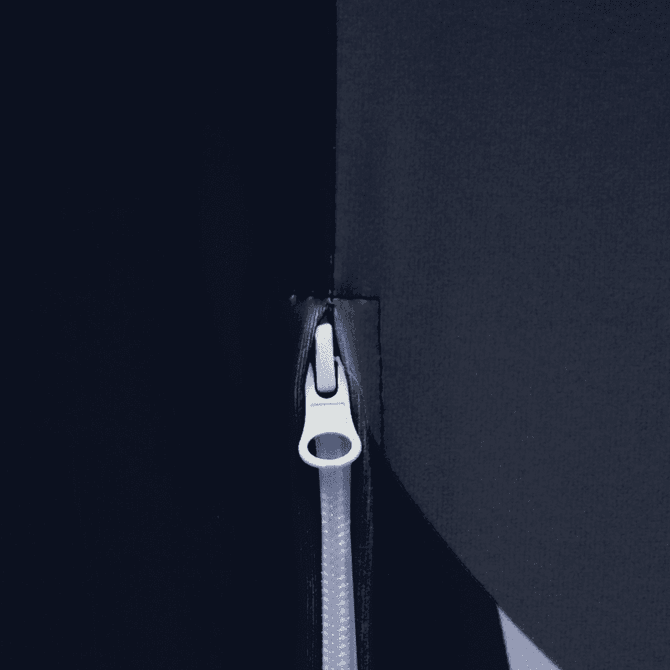 A close-up of a zip on a dark fabric, featuring a silver pull tab against a contrasting background.