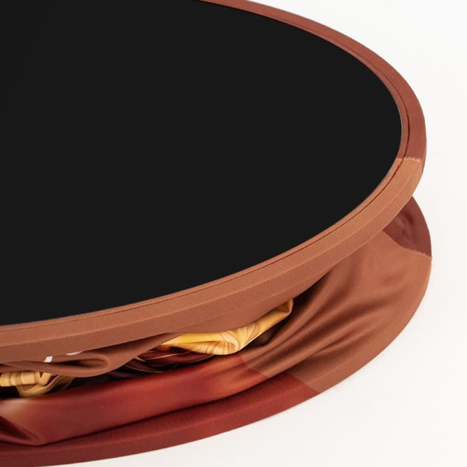 A round display counter with a black top and a fabric cover in shades of brown and gold, featuring a logo.