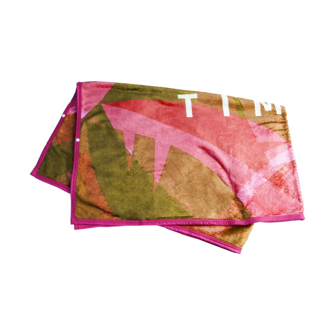 A flannel blanket featuring a design with pink and earthy tones, bordered in pink. It has a logo on one corner.