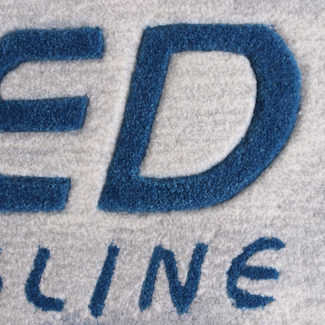 Acrylic fibre logo mat in grey and blue, featuring a prominent logo design.