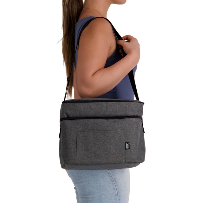 A grey cooler bag with a shoulder strap, featuring a front pocket and branding, carried by a person.